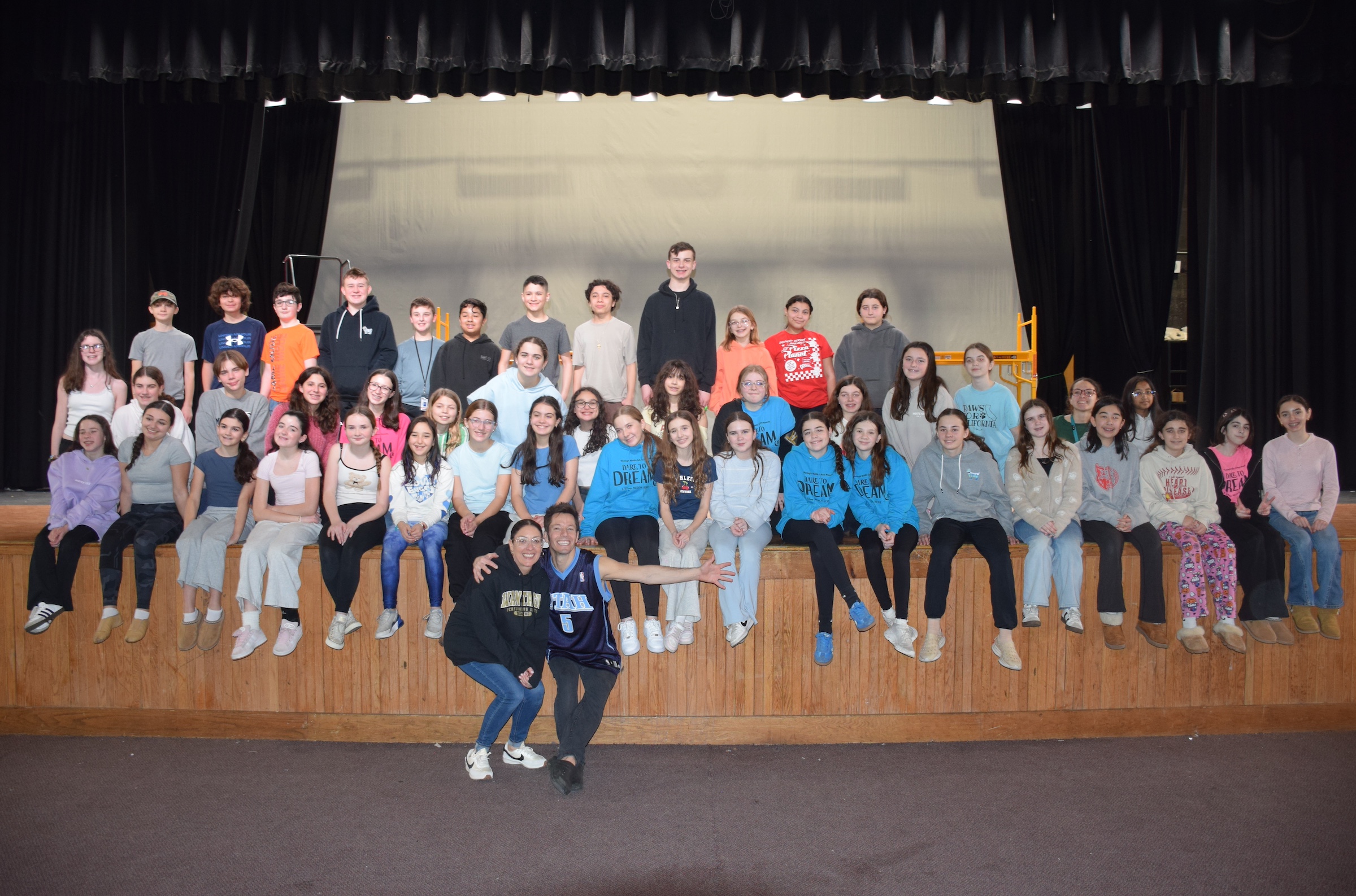 kids sitting on edge of stage smiling